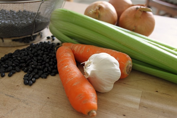 Carrots, celery, and onions on a cutting board