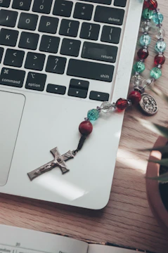 A warm, inviting workspace with a laptop open to a community forum page, surrounded by notes and a rosary.