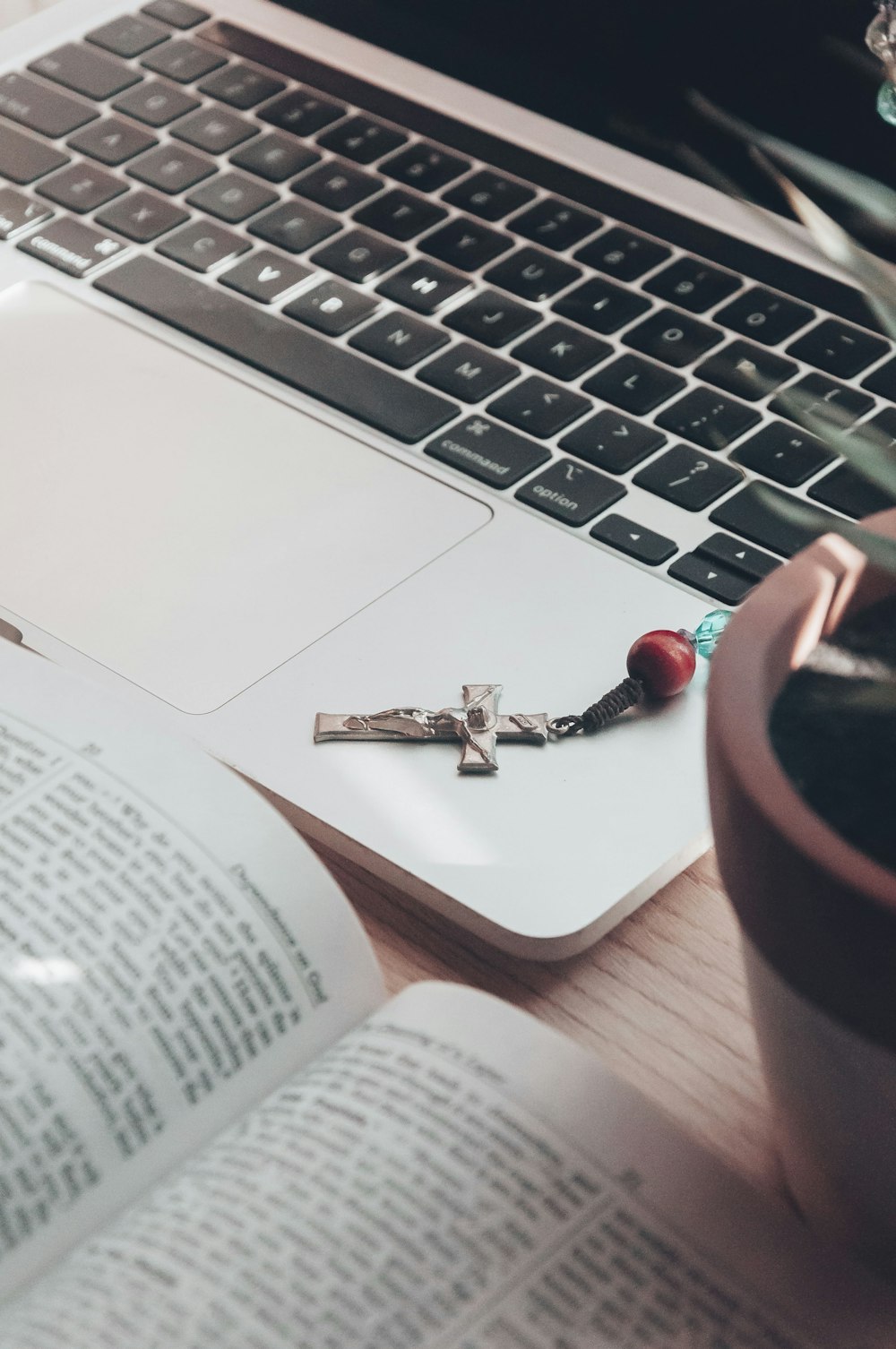 a cross on a book next to a laptop