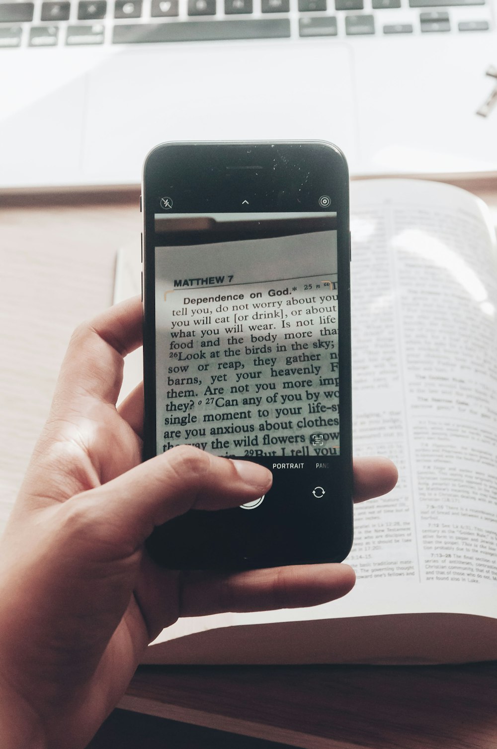 a person holding a cell phone in front of a book