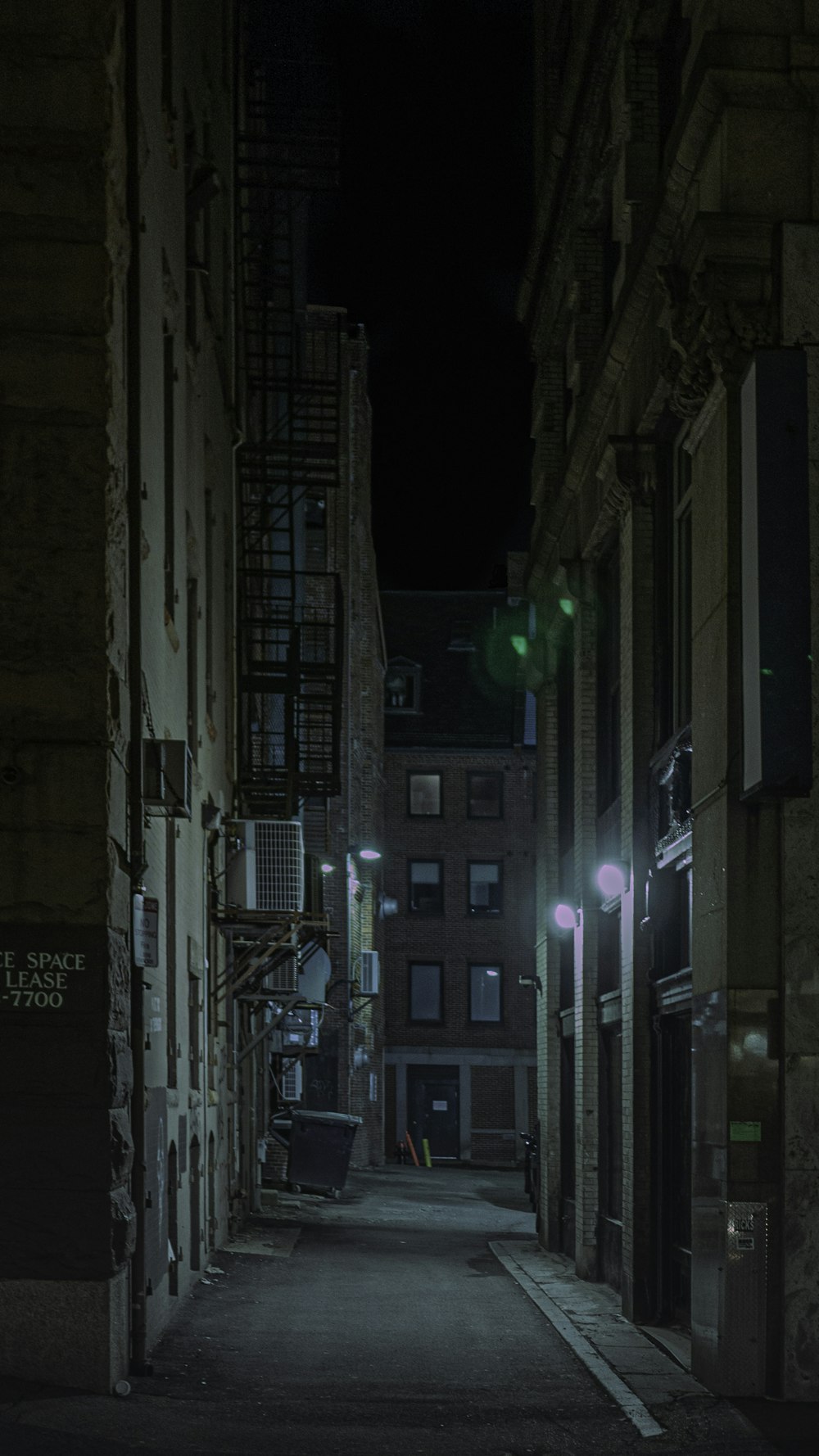 a dark alley way with buildings and a street light