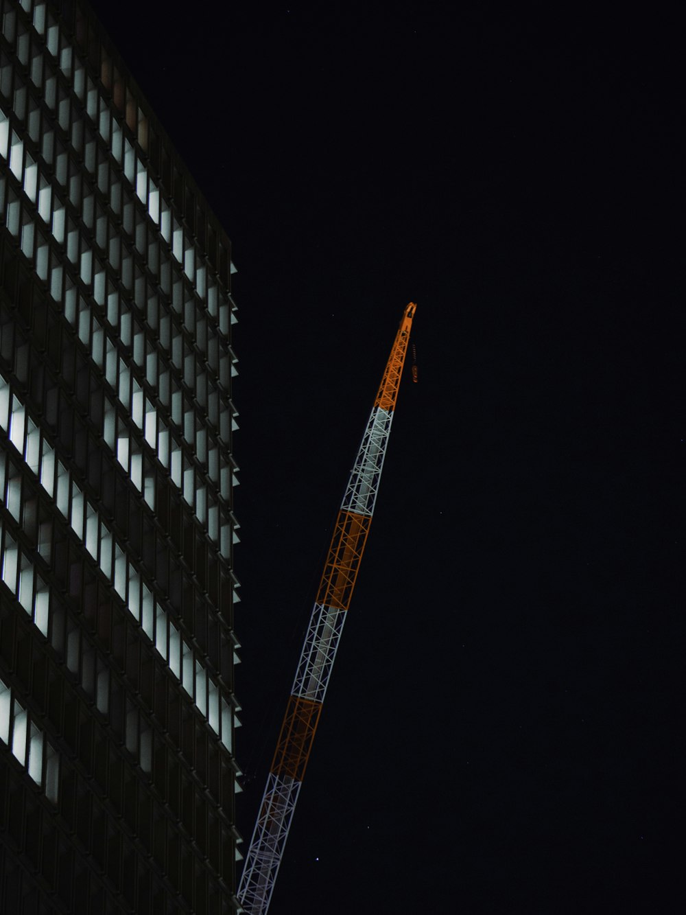 a crane is in the air next to a tall building