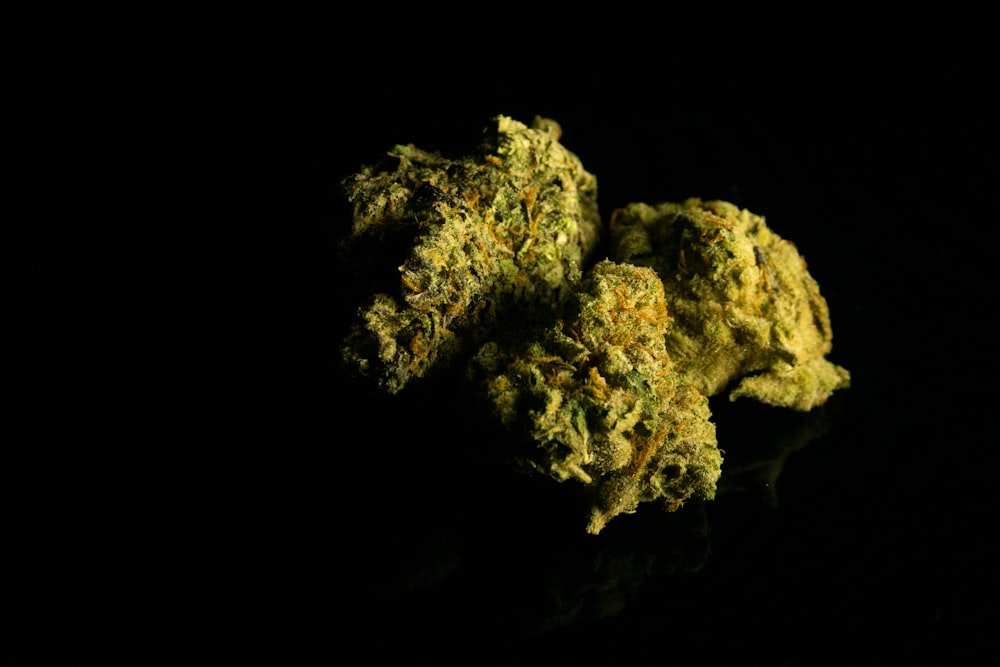 a close up of two marijuana buds on a black surface