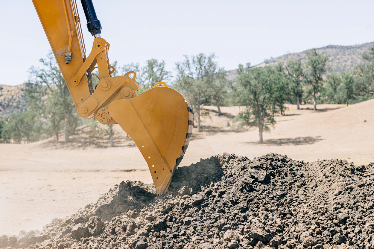 An excavator bucket digging into a pile of dirt