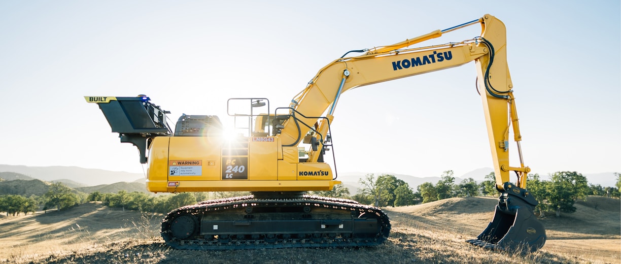 a yellow excavator sitting on top of a dirt field