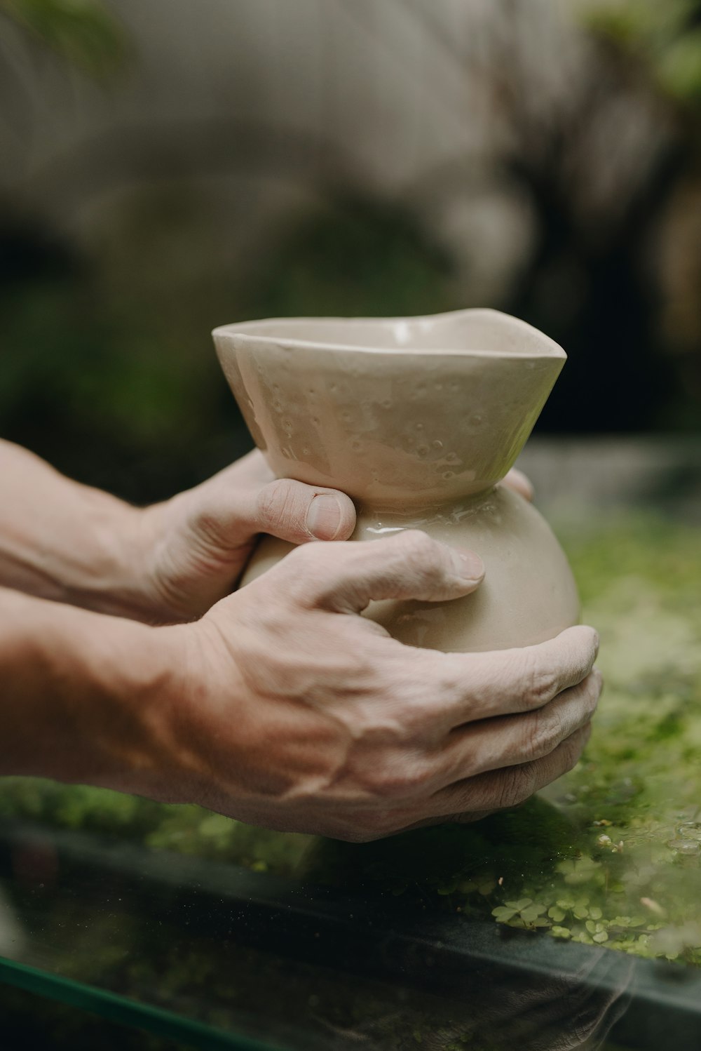 a person holding a white vase in their hands