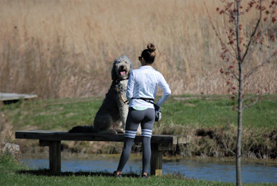 a woman sitting on a bench next to a dog