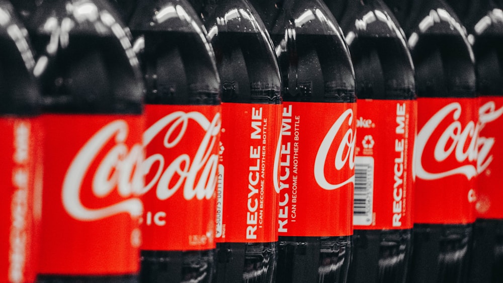 a row of coca - cola bottles lined up on a shelf