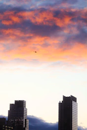A luxury helicopter flying over Dubai’s skyline at dusk with desert dunes in the background.