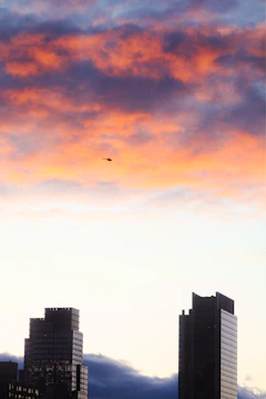 A luxury helicopter flying over Dubai’s skyline at dusk with desert dunes in the background.