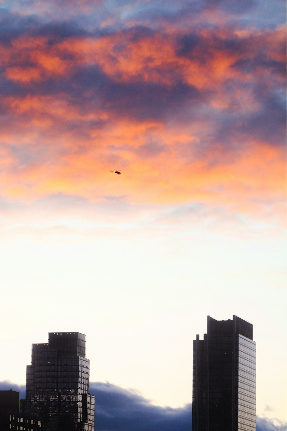 a plane flying in the sky over some tall buildings