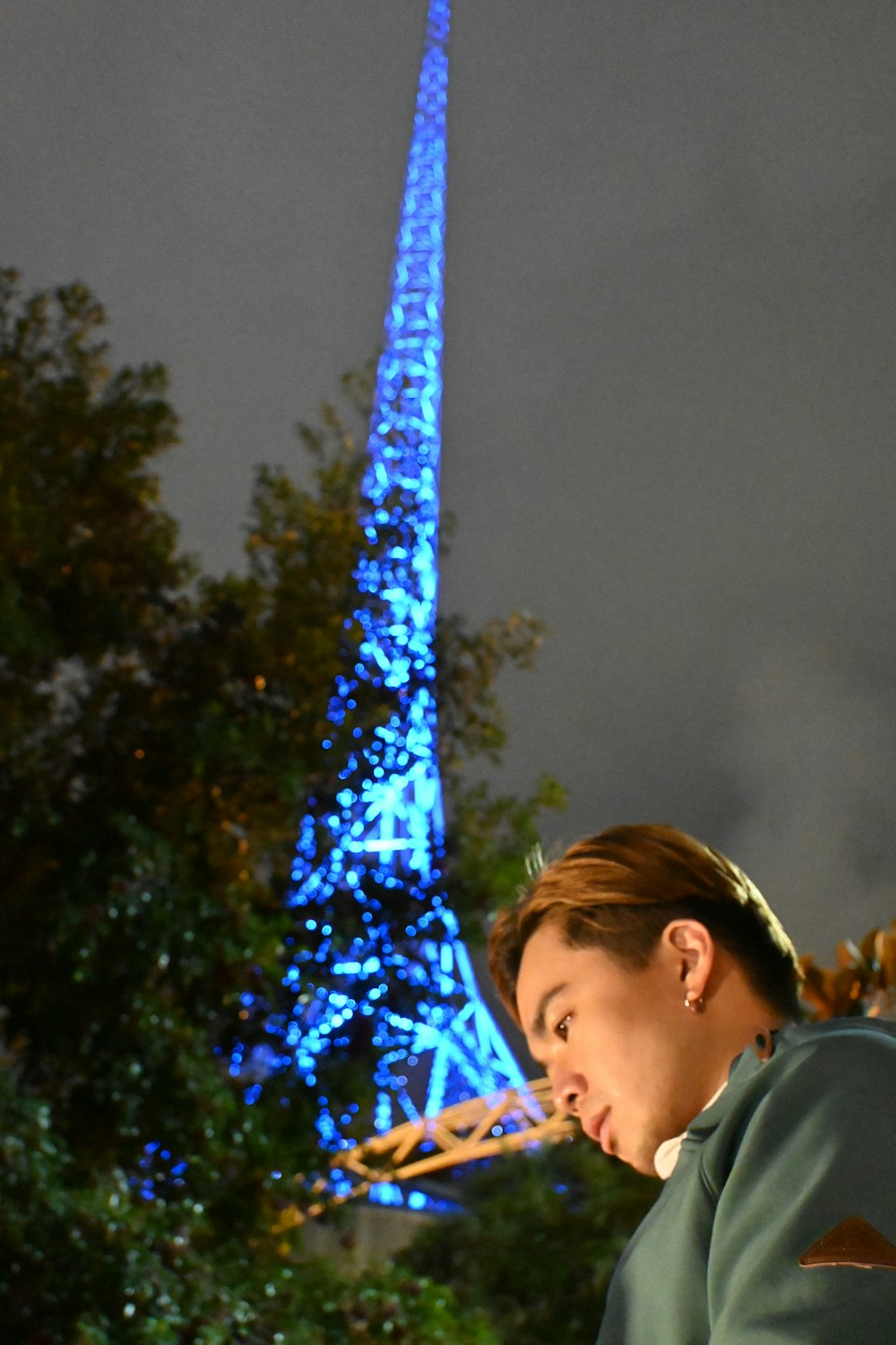 a woman looking at her cell phone in front of the eiffel tower