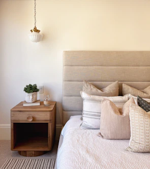 A cozy bedroom scene featuring a bed layered with various Dreamnest pillows and matching cases.