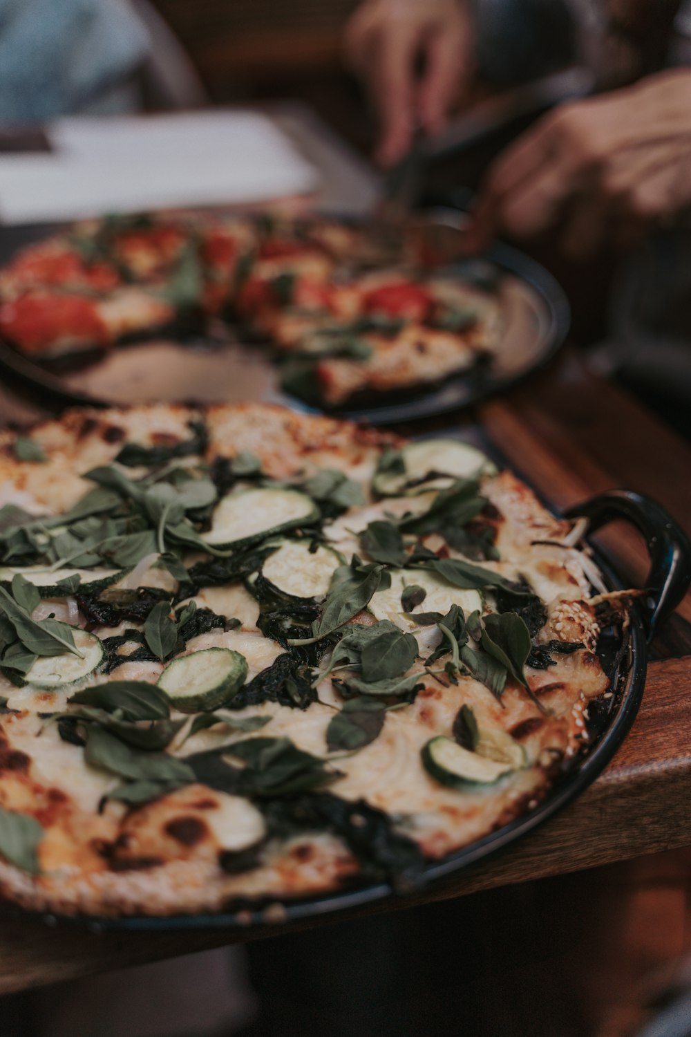 a couple of pizzas sitting on top of a wooden table