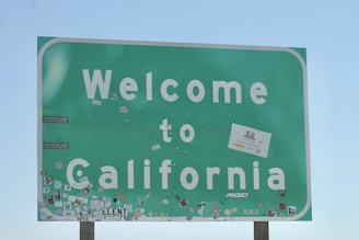 a welcome to california sign with stickers on it