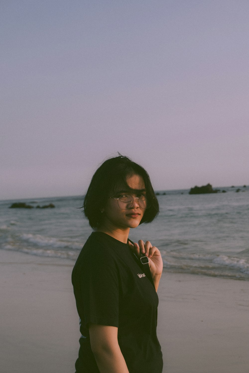 a woman standing on a beach next to the ocean