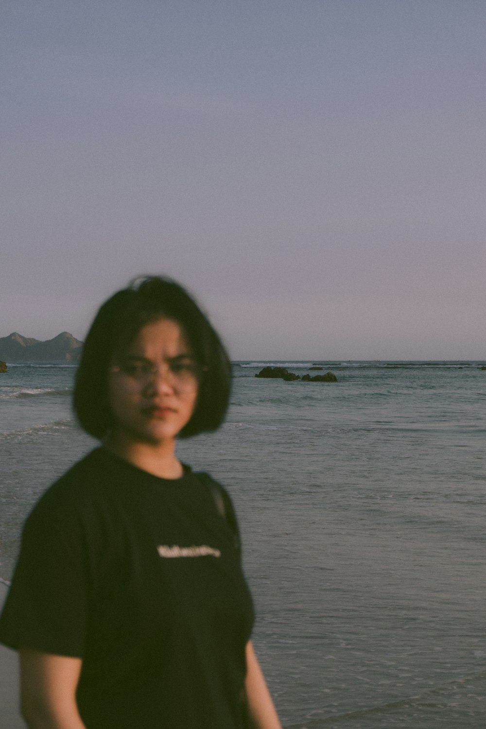 a woman standing on a beach next to the ocean