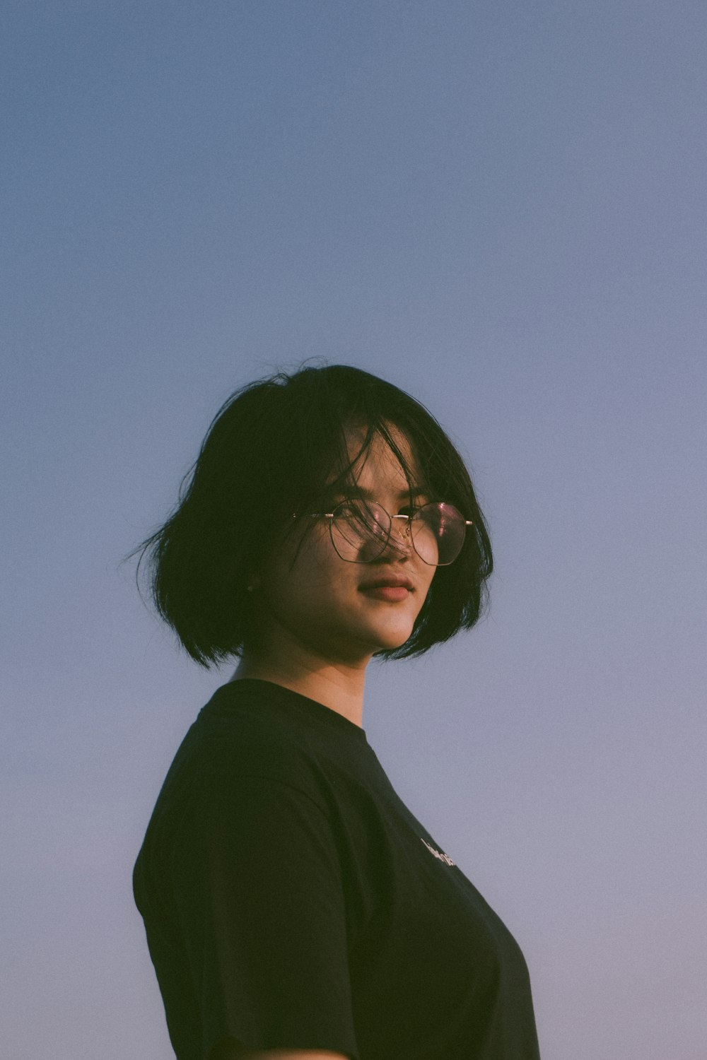 a woman wearing glasses standing in front of a blue sky