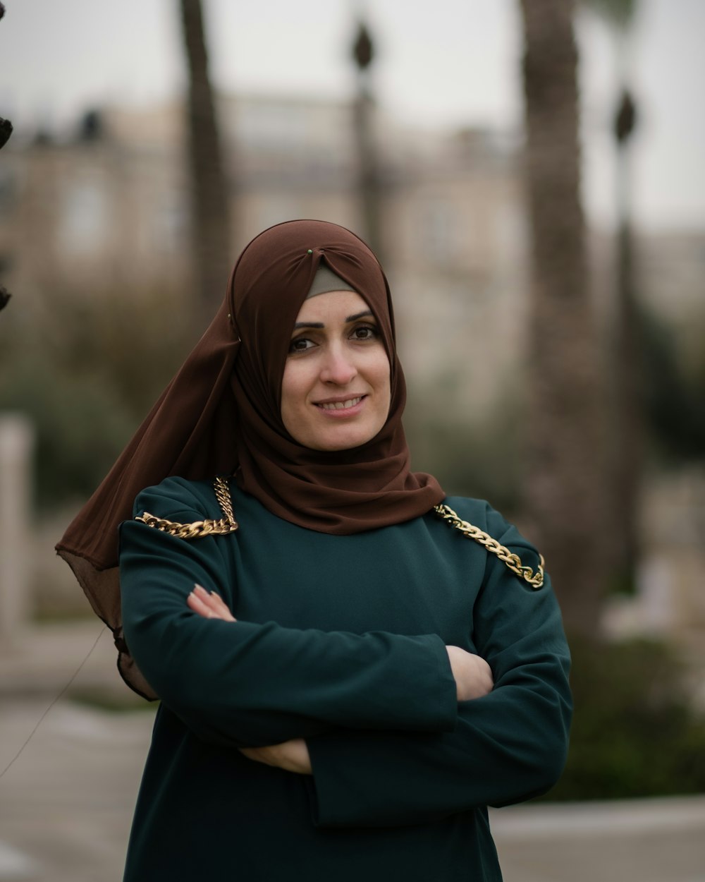 a woman in a hijab standing with her arms crossed