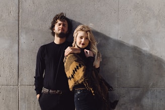 a man and a woman leaning against a wall