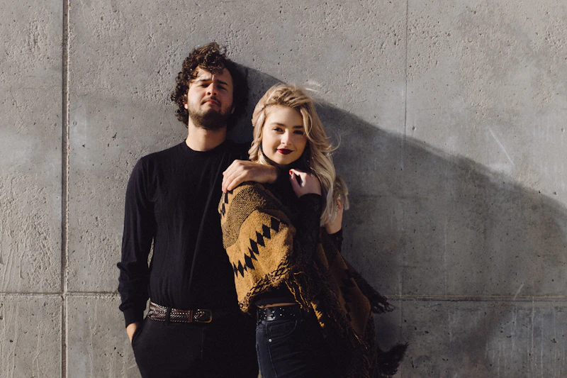 stylish couple leaning together against a wall