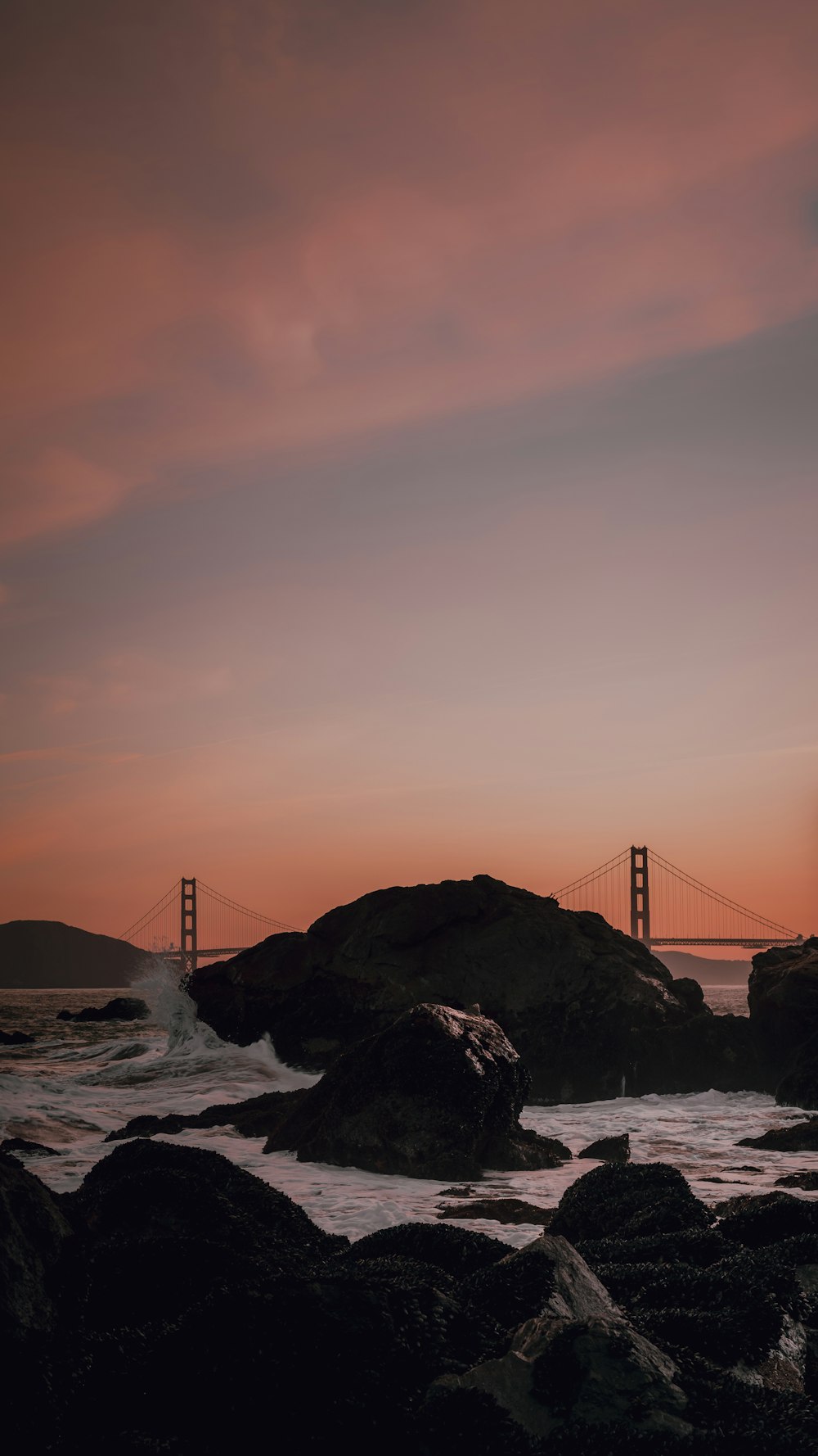 the golden gate bridge in the distance as the sun sets