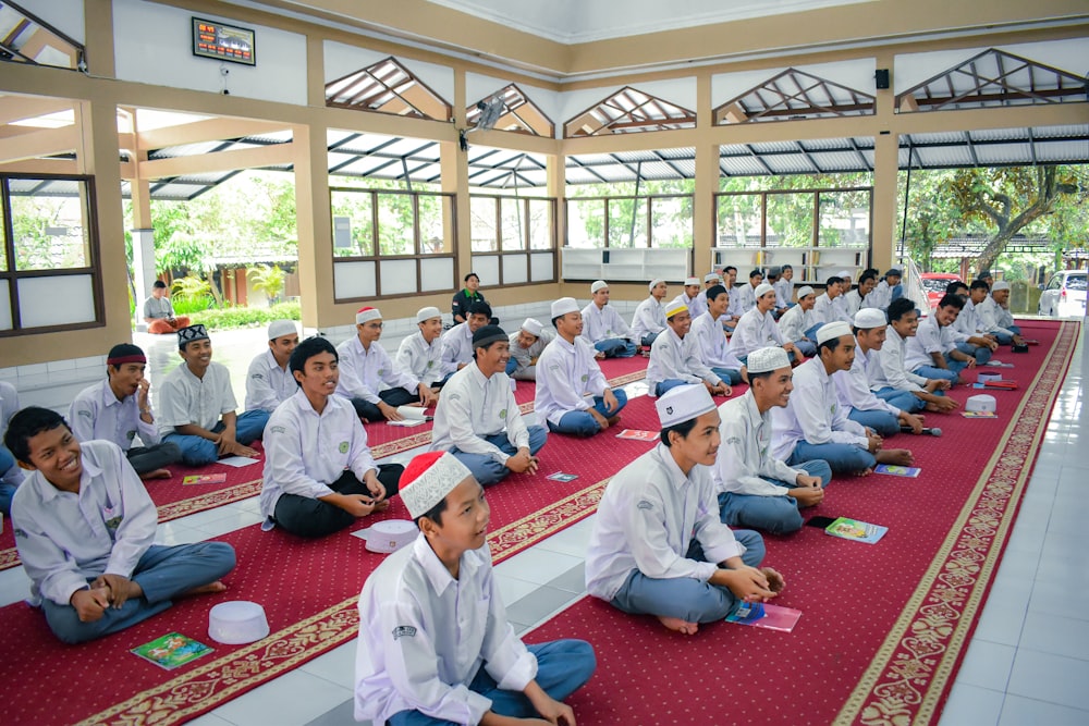 a group of men sitting on top of a red rug