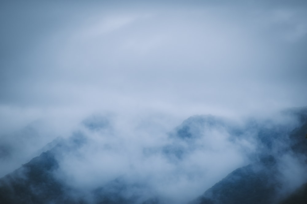 a mountain covered in fog and clouds under a cloudy sky