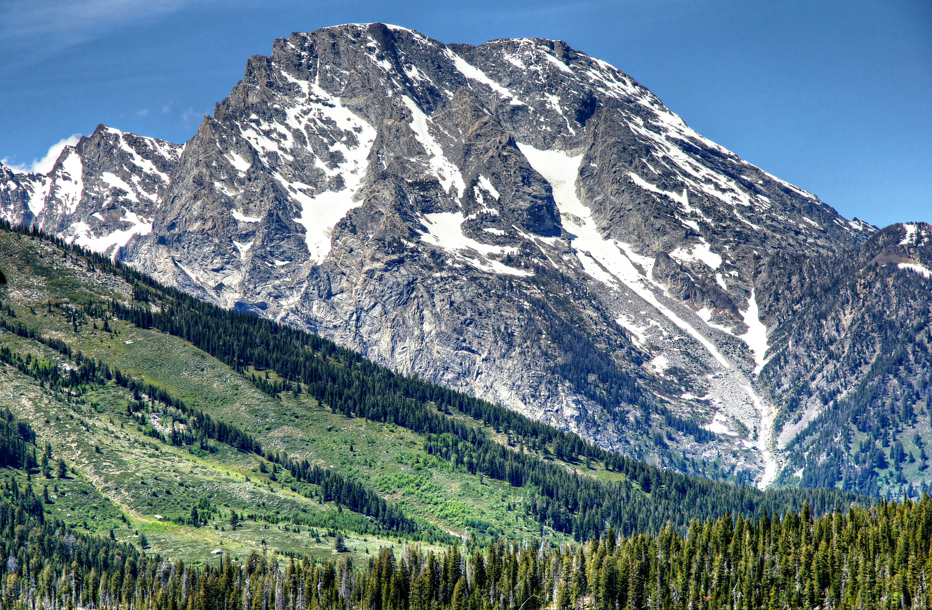 a large mountain with a forest below it, Grand Teton National Park - 1638</p><p>Grand Teton National Park lies in Northwestern Wyoming about ten miles south of Yellowstone National Park.