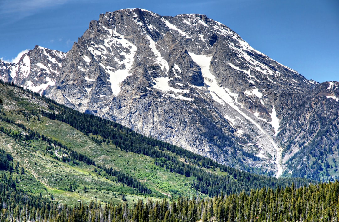 a large mountain with a forest below it, Grand Teton National Park - 1638</p></figure><p>Grand Teton National Park lies in Northwestern Wyoming about ten miles south of Yellowstone National Park.
