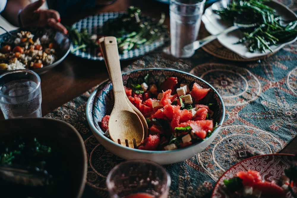 a bowl of watermelon salad with a wooden spoon