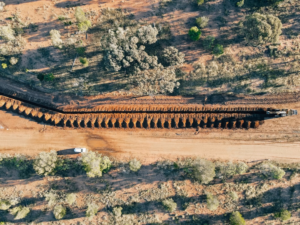 a truck driving down a dirt road next to a forest