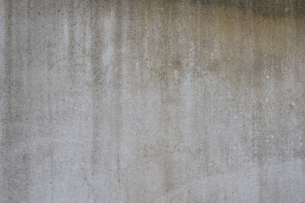 Una persona caminando por una calle junto a una pared de cemento