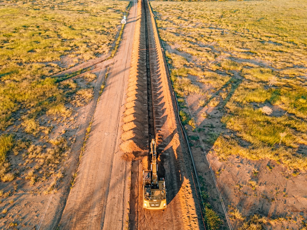 a truck driving down a dirt road next to a field