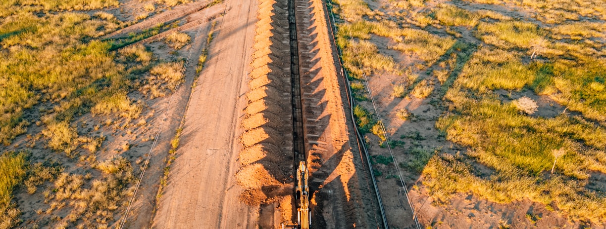 a truck driving down a dirt road next to a field