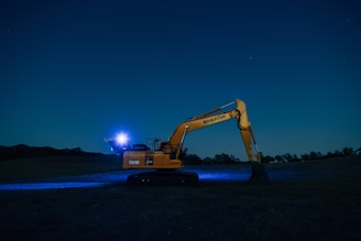 an excavator is parked in a field at night