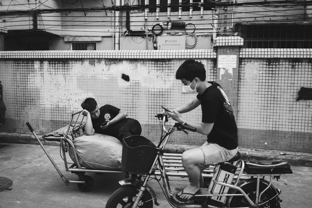a boy riding a bike with a bed on the back of it