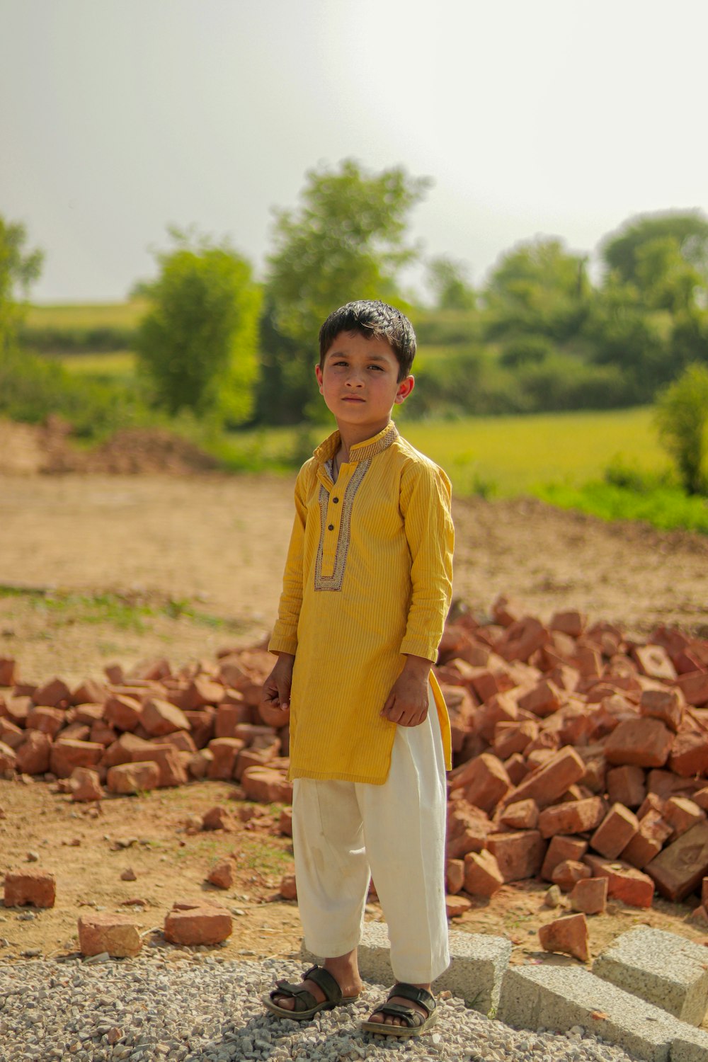 a young boy standing in front of a pile of bricks