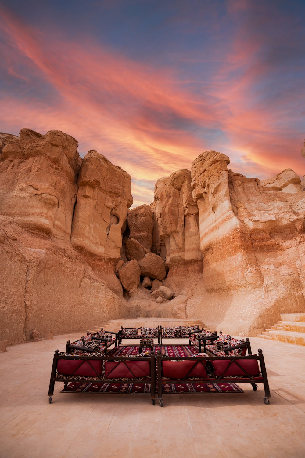 a red couch sitting in the middle of a desert