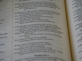 A close-up view of an open book displaying printed text. The text is formatted in two columns, with emphasis on specific numbers indicating sections or verses. The page appears slightly curved, suggesting the book is open flat.
