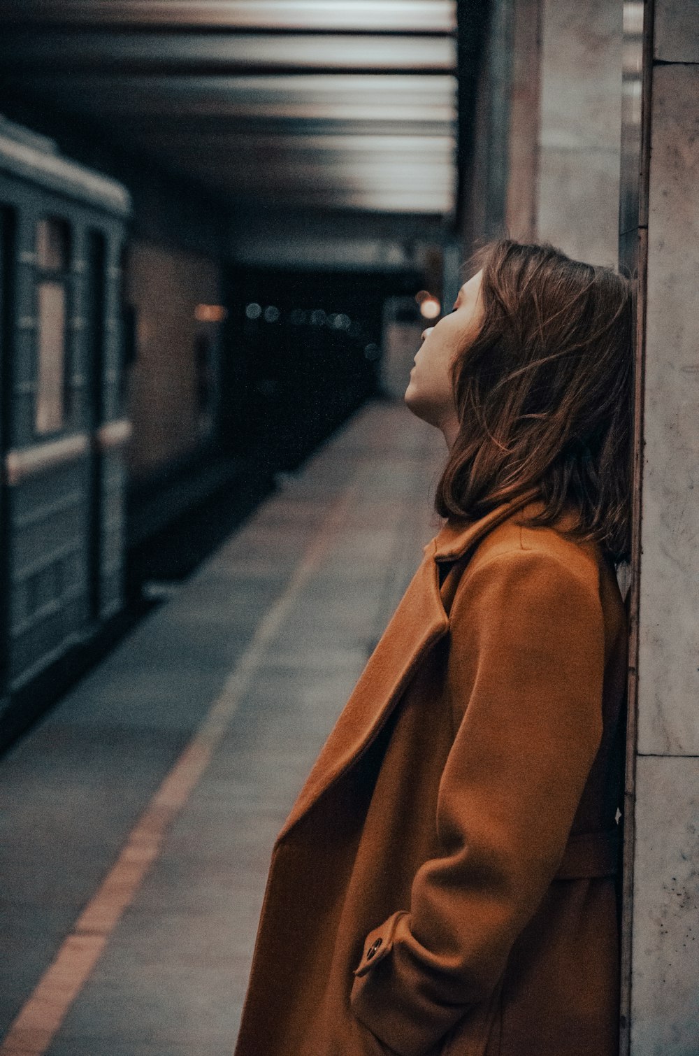a woman standing in a subway station next to a train