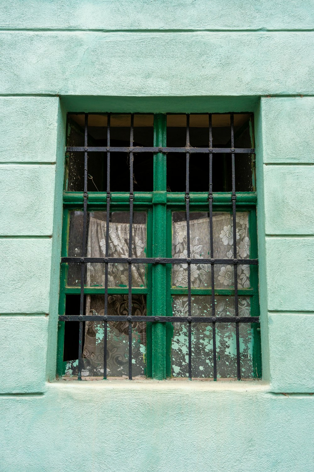 una ventana verde con rejas a los lados de la misma