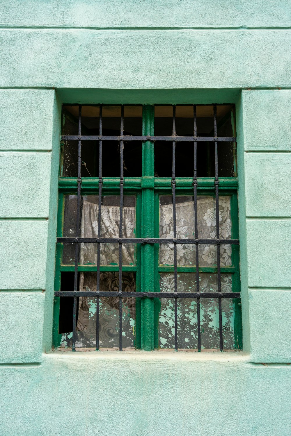 uma janela verde com barras nas laterais