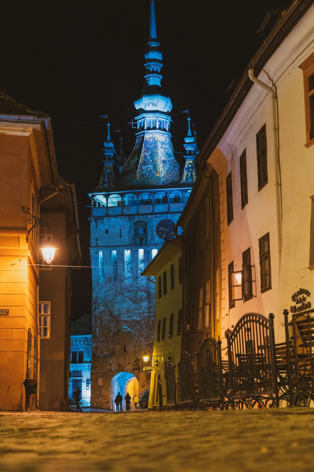 a city street at night with a clock tower in the background