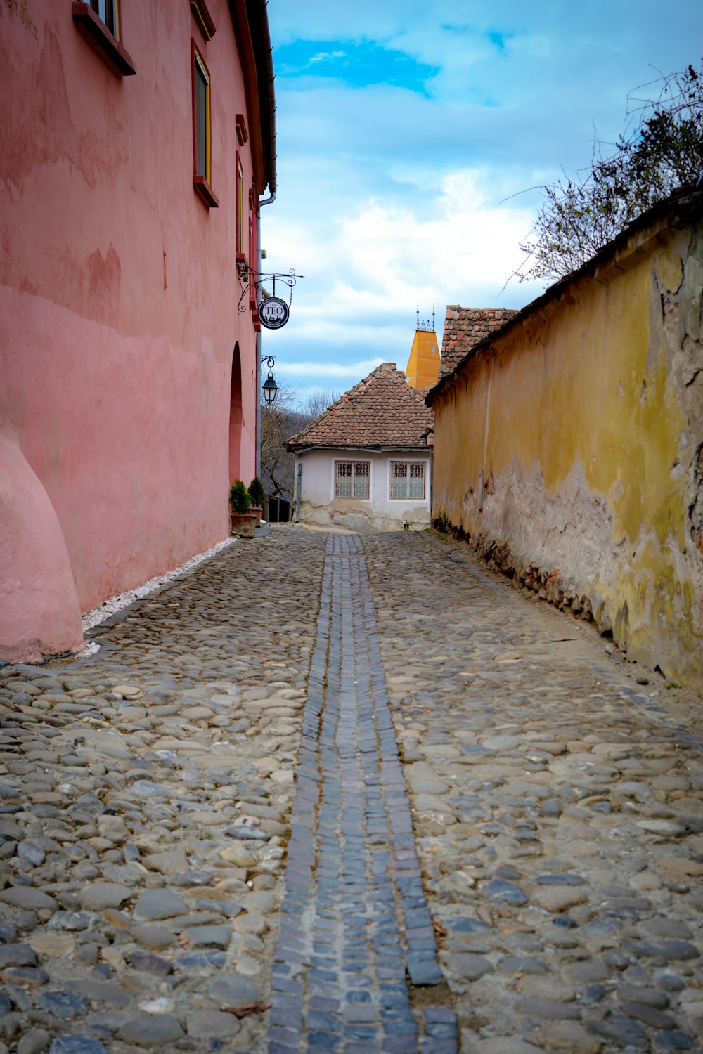 a cobblestone street with a pink building in the background