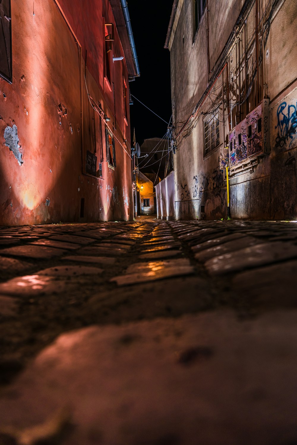 a narrow alley with graffiti on the walls