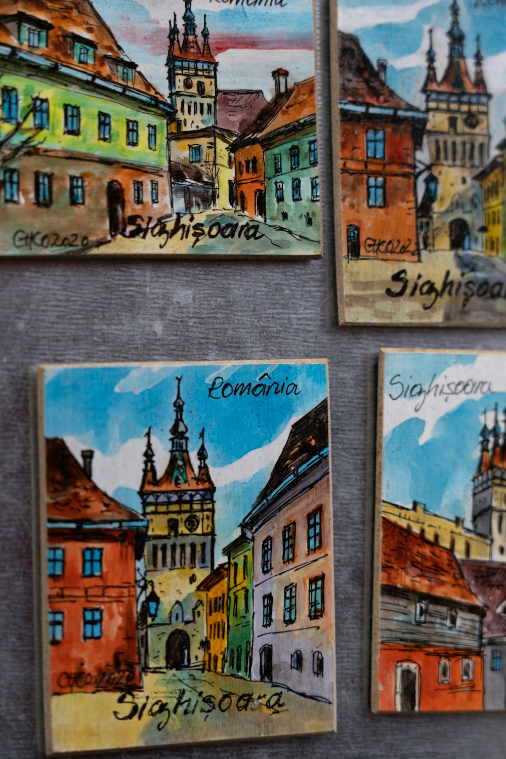 a group of four paintings of buildings on a wall