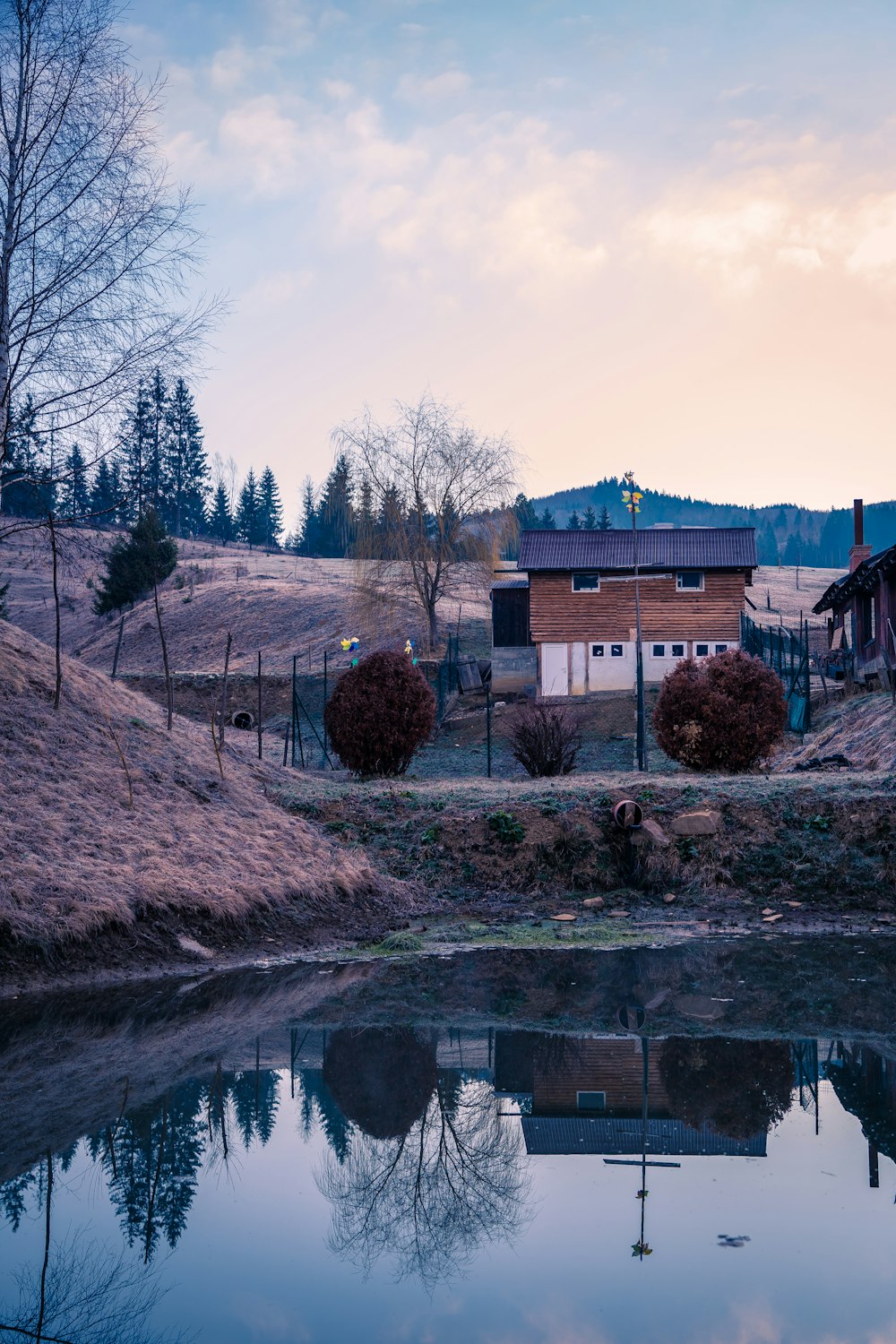 a house sitting on top of a hill next to a lake