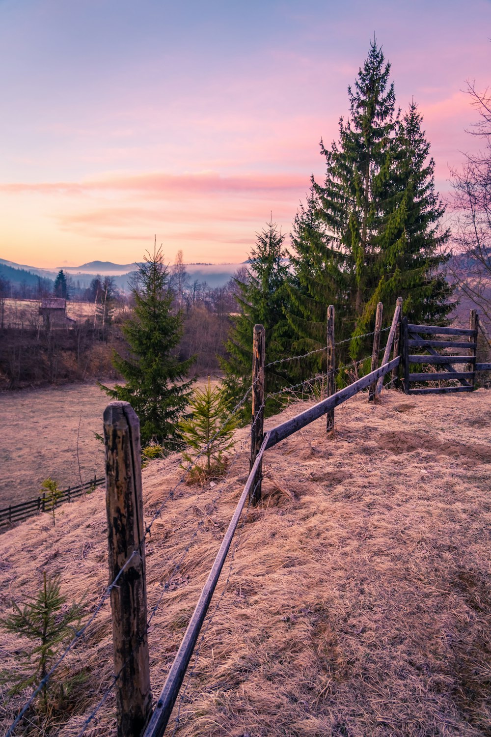 une clôture en bois sur une colline avec un coucher de soleil en arrière-plan