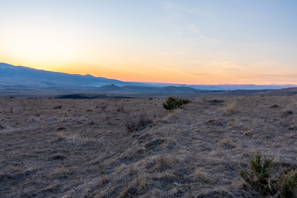 the sun is setting over the mountains in the distance